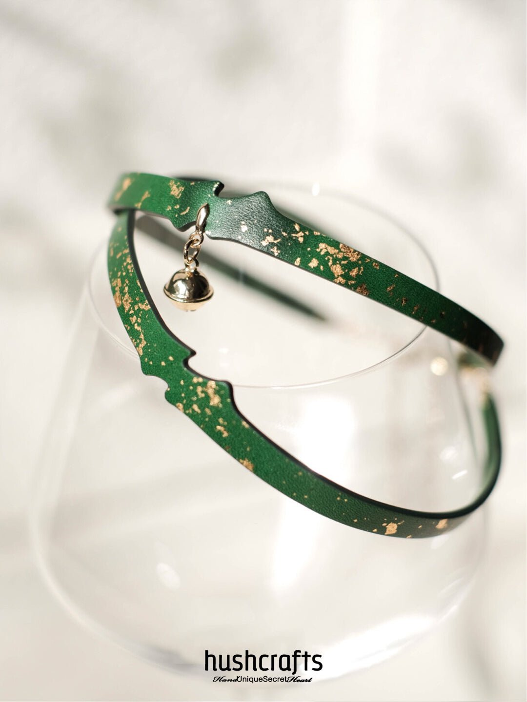 Green leather choker day collar by HushCrafts – lightweight and refined, with gold leaf pattern and a dangling bell charm.