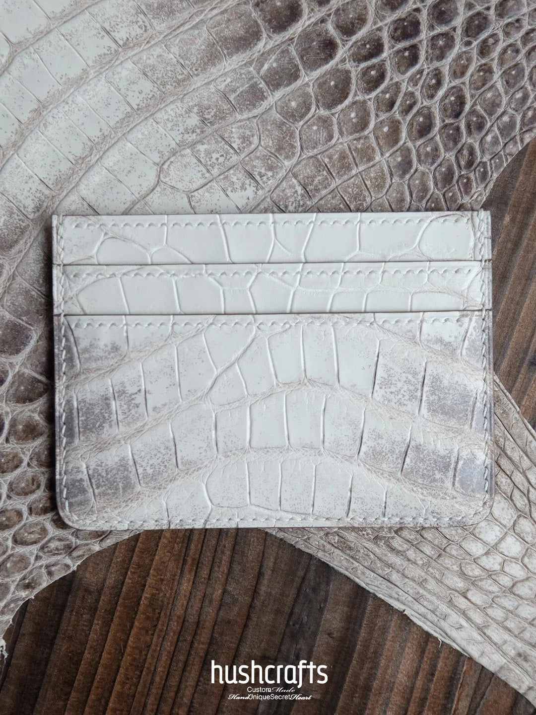 White crocodile texture cardholder on a textured surface with 'hushcrafts' branding.