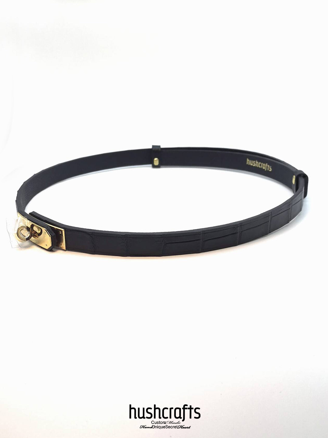 Black belt with gold buckle on a white background, featuring the brand 'hushcrafts'.