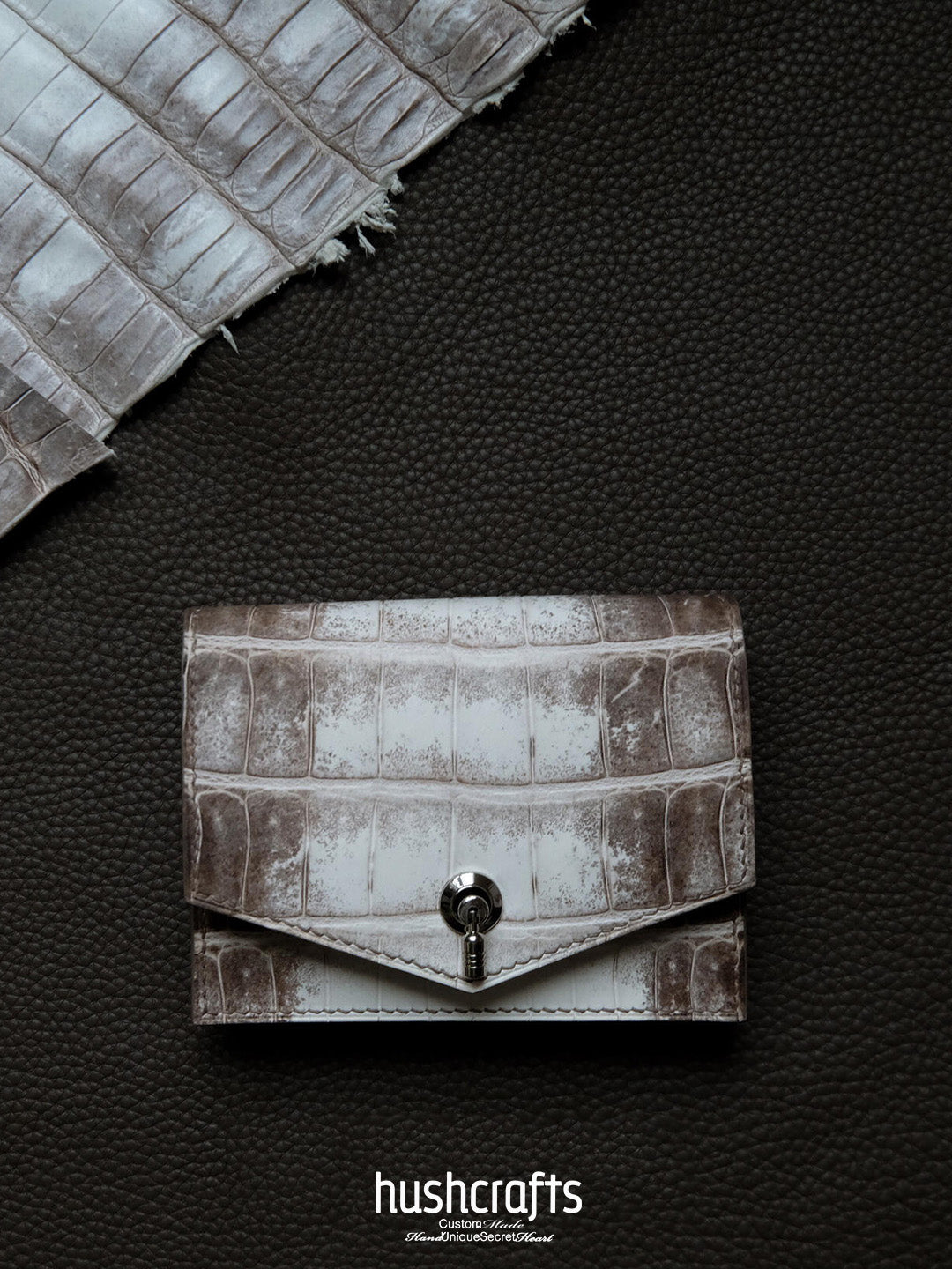 White crocodile skin wallet on a dark textured background with 'hushcrafts' branding.