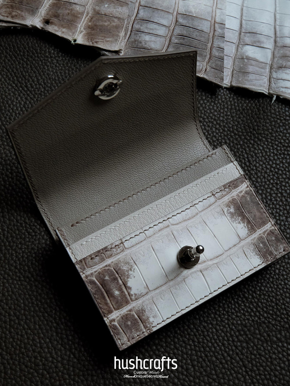 Close-up of a textured leather wallet with 'hushcrafts' branding on a dark background.
