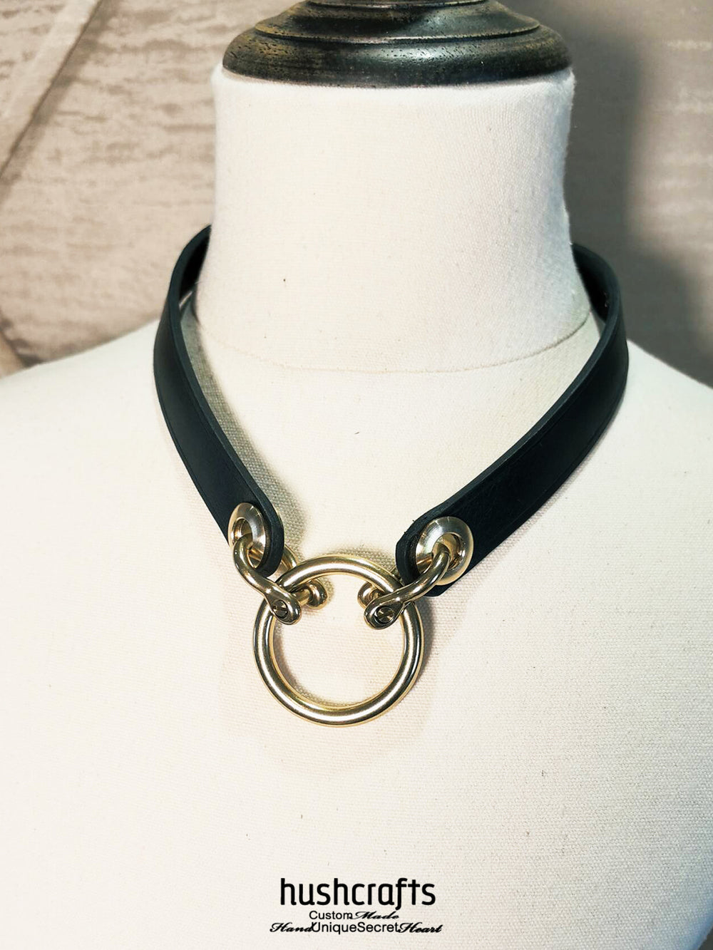 Black leather choker with gold rings on a mannequin, branded 'hushcrafts'.
