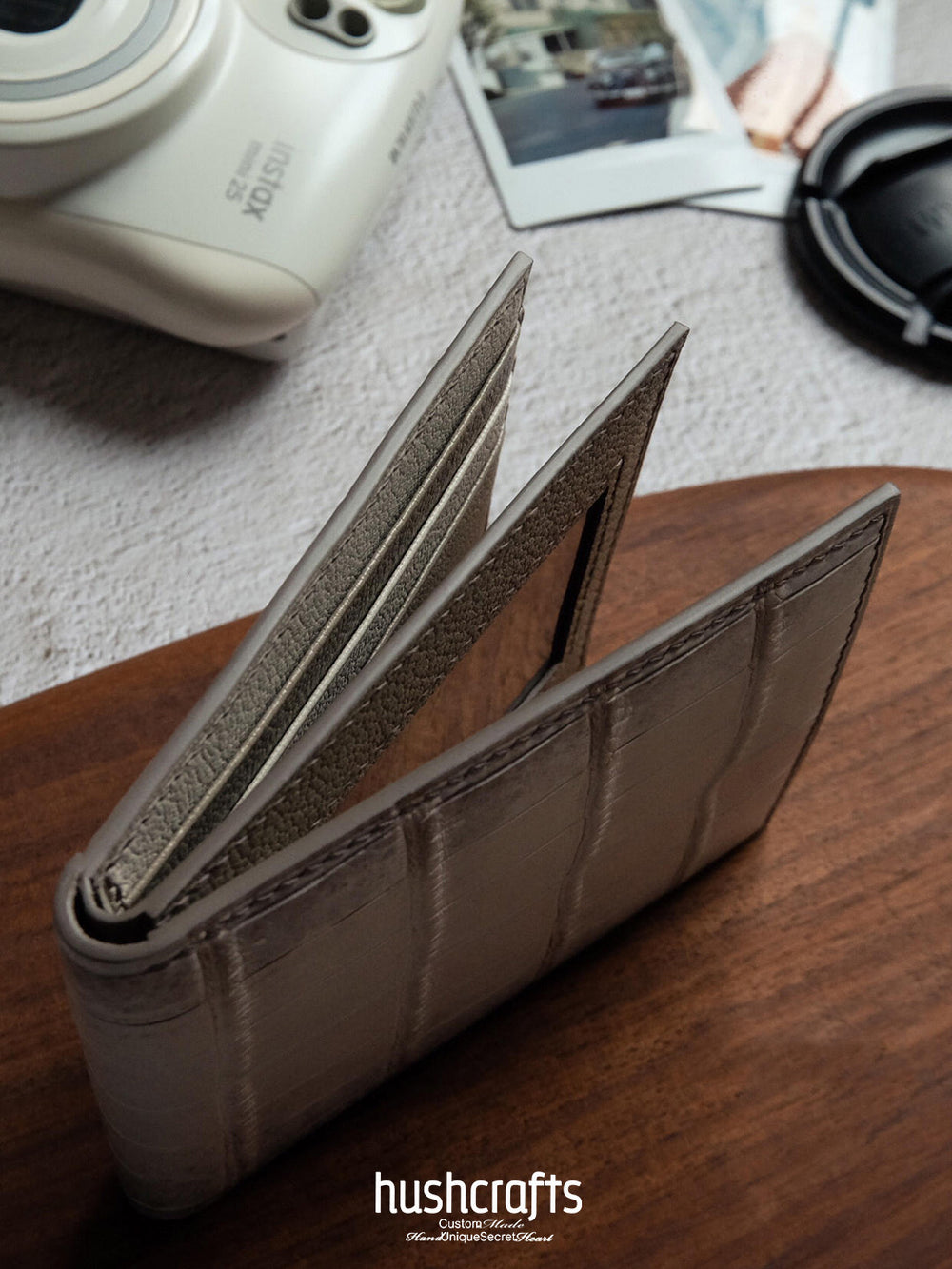 Light gray wallet with 'hushcrafts' branding on a wooden surface.