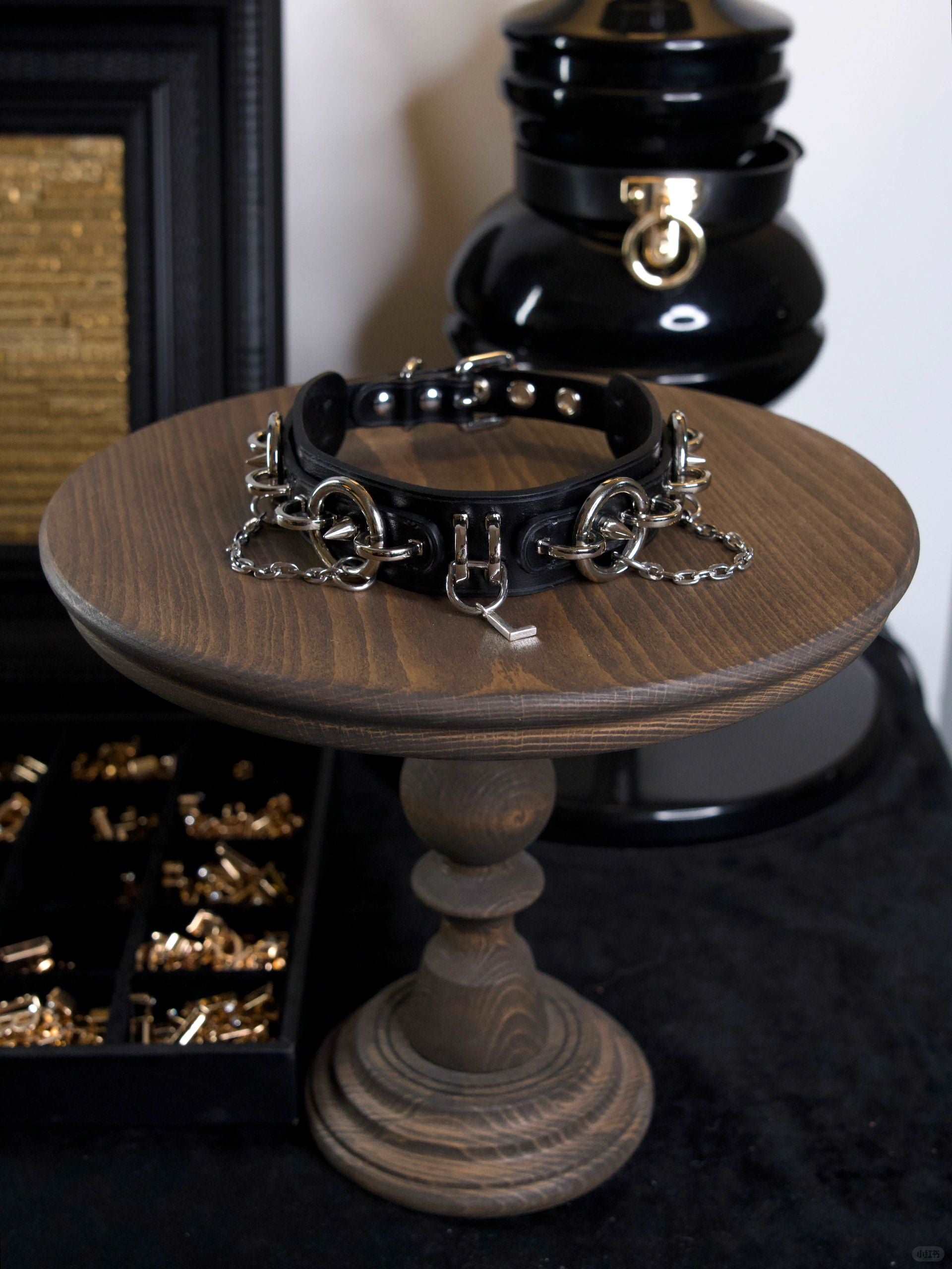 A black leather collar with intricate silver rings and chains, designed for women in submission. This sex collar ensures a secure fit, emphasizing both comfort and restraint. HushCrafts provides a guide on how to measure your neck collar for the perfect size.